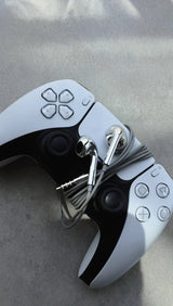 Azuro chrome earbuds resting on a game controller